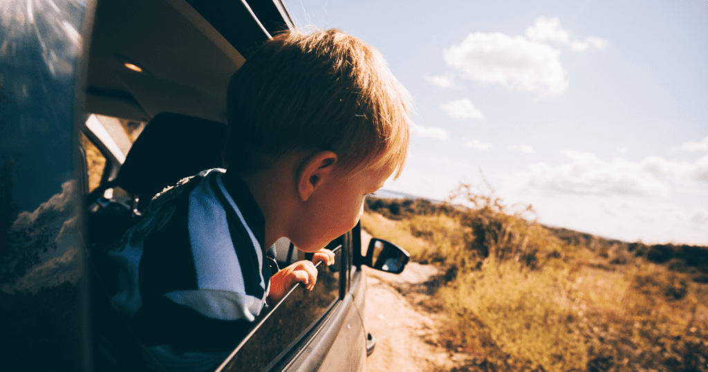 kid looking out the window on road trip with family 